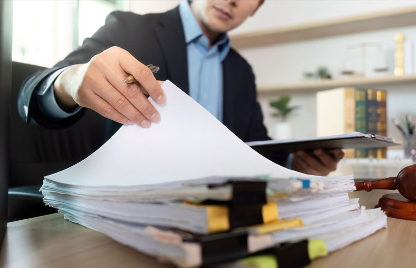 A person in a suit handling a pile a documents